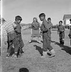 [Group of children playing outdoors with their instructor, Kinngait, Nunavut] [between 1956-1960]