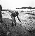 [Barbara Hinds balancing on a rock with a fishing pole] [between 1956-1960]