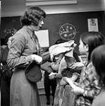 [Young woman handing out Brownie uniforms to a group of girls, Iqaluit, Nunavut] 1960