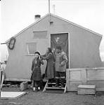 [Girl Guide Kootook standing outside with her parents, Iqaluit, Nunavut] 1960