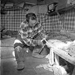 [Inuksiak making fishing nets inside a tent, Iqaluit, Nunavut] 1960