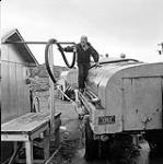 [Tube spraying water onto a truck, Iqaluit, Nunavut] 1960