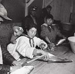 [Women preparing fish while two men observe the work, Killiniq, Nunavut] 1960