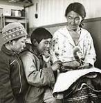 [Emily showing a toy duck to two young boys, Killiniq, Nunavut] 1960