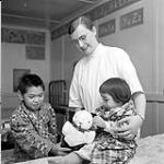 [Occupational therapist with two children at the Anglican Mission Hospital, Aklavik, Inuvialuit, Northwest Territories] 1956
