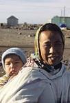 Femme [Rosanne Oqutaq Kinniksie.] inuite portant un enfant [Suzanne Kinniksie], à Arviat.  1979.