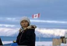 Woman in front of Canadian flag, Pond Inlet 1979.