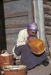A First Nation Elder making a birch bark basket. [Aîné des Premières Nations fabriquant un panier d'écorce de bouleau.] [entre 1942 et 1959].