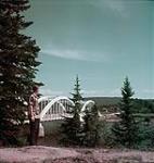 Man standing on riverbank looking at the Humber River Bridge at Deer Lake July 1949