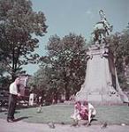 Two female tourists feeding pigeons in Dominion Square, Montréal June 1950