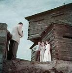 Man taking photograph of one man and two women at the old fort on St. Helen's Island under the Jacques Cartier bridge, Montréal July 1950