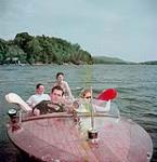 Deux hommes et deux femmes font du bateau à moteur sur le lac Massiwippi, au Québec juillet 1950