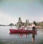 Father, mother and two little girls fly fishing in a boat on Story Lake, Ontario août 1951