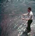 Un touriste pêche sur la rive du lac Tremblant dans les Laurentides December 1951