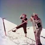 Surveying party, A. Wright (left), and A. Kalbus, charts route of transmission line through snow-covered Kildala Pass, British Columbia July 1952