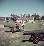 Man, woman and young child seated on a canon at Fort Anne National Historic Park, Annapolis Royal, Nova Scotia 1952