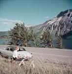 Mrs. C. Hamill paints a scene from roadside in Waterton Lakes National Park, Alberta  [Mme C. Hamill, sur le côté de la route, peint le panorama dans le parc national des lacs Waterton, en Alberta] 1952