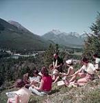 Murray MacDonald, arts instructor, Banff School of Fine Arts, conducts class in landscape painting above town of Banff, Alberta 1952