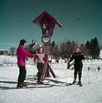 Un skieur et deux skieuses lors d'un cours dans un centre de villégiature d'hiver dans les Laurentides au Québec février 1953