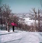 Les skieurs Suzanne Parent et Marc Cloutier se préparent à descendre du sommet du mont Kingston dans les Laurentides près de Ste-Agathe, au Québec février 1953