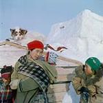 Femme inuite [Alacee Nungaq] portant un amauti et trois enfants [Philip, Annie et Anna Levi] à l'extérieur en vêtements d'hiver, à Resolute Bay (Territoires du Nord-Ouest) [Resolute Bay (Qausuittuq), Nunavut]. mars 1956