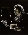 Photo de tournage d'un acteur tenant un livre et gesticulant de la main [ca. 1970-1978]