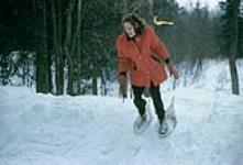 Audrey James snowshoeing down a hill during a race. Shilly Shally Lodge, Gatineau Park 1963