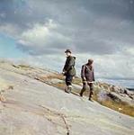 Two men walking on a rocky slope, Norway House, Manitoba. [The man on the right has been identified as Jimmy Spence, a Cree trapper and guide.] [between 1955 and 1963].