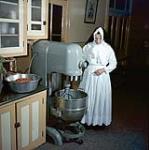 Religieuse utilisant un mélangeur industriel dans la cuisine au couvent Notre-Dame, Sherbrooke, Québec 1957