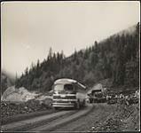 Daily Calgary bus passes through a blasting area in Kicking Horse Canyon. Travel is between hours of 5pm and 8am only on this stretch 1954.