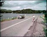 Tourists stop for photograph at Lake Massiwippi, on Quebec's No.1 highway.  juillet 1950.
