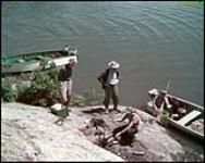 Fishermen prepare a quick meal on an island in the Lake of the Woods district of Ontario. juillet 1950.