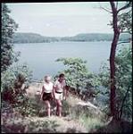 Strolling along the shore of Lake Rosseau near Wigwassan Lodge in the Muskoka Lakes district, Ontario. [Une promenade le long de la rive du lac Rosseau près de <<Wigwassan Lodge>> dans la région des lacs Muskoka, Ontario.] juillet 1951.