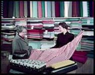 At the Riopel Fabric Centre, Ottawa, Mrs. M. Kelso waits on a customer.  janvier 1955.