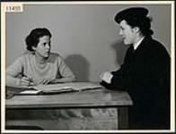 Wren Gwynneth Speedie in uniform being interviewed by rehabilitation officer Margaret Gourley in Toronto April 1945