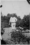Wilson P. MacDonald in a garden, holding a golf club [1926]