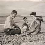 [The Houston family sitting on a rocky beach] 1960