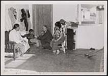 Dr Gordon Butler en train d'examiner un jeune garçon autochtone sous le regard attentif de deux femmes autochtones [ca 1950-1964]