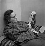 Helen Salkeld reading on a bed
 août 1954.