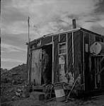 Carter Construction, homme debout dans le cadre de porte d'une baraque à Regina (Saskatchewan) 10 août 1954.