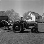 Albert Gruenke sitting on a tractor, Steinbach, Manitoba June 1, 1956.