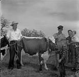 Eugene Derksen with Louis Yvon's family and their two newly donated cows in Saint Labre, Manitoba June 2, 1956.