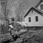 Mrs. Borne hanging clothes, Steinbach, Manitoba June 1, 1956.