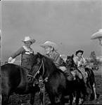 Three young cowboys sitting on horses during the Swan River round-up, Manitoba 30 June 1956.