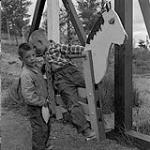 Boys on a horse swing, Flin Flon, Manitoba June, 1956.