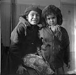 Gros plan de deux enfants [cris] portant des manteaux à l'intérieur, Buffalo Narrows (Saskatchewan) March 1955.