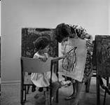 Teacher Jackie Otis holding a girl's painting during an art class, Calgary Allied Arts Centre août 1962.