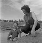 Woman with child in the water, Swan River, Manitoba June 23, 1956.