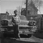 Garçon debout devant une voiture 1958.