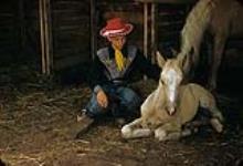 Cowboy agenouillé près d'un poulain Palomino au rassemblement de bétail de Swan River, Manitoba 30 juin 1956.